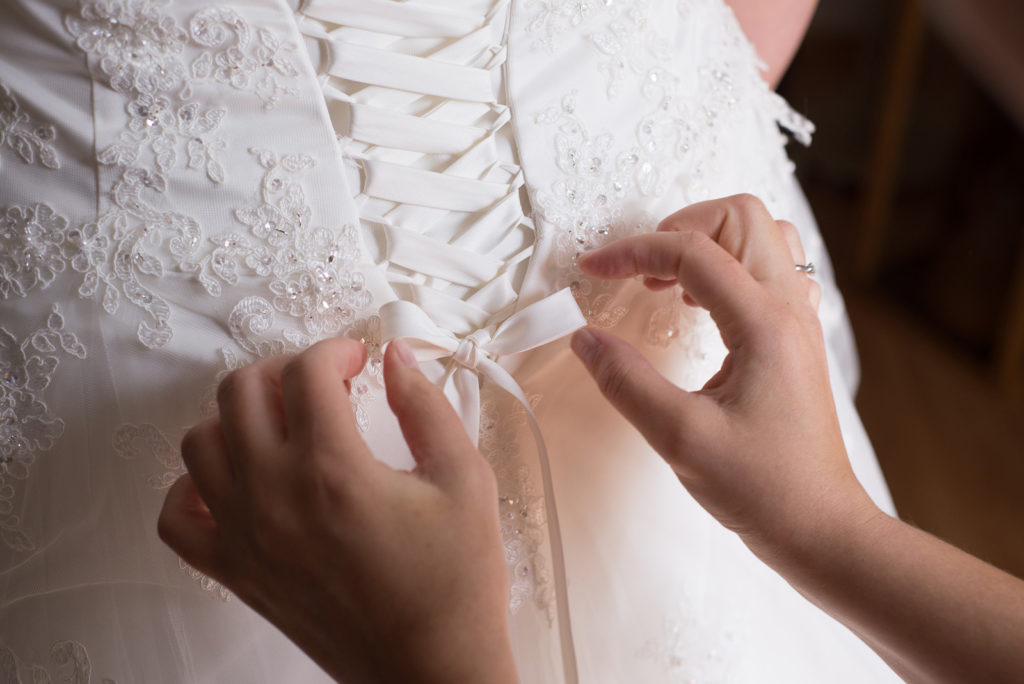 Schleifen binden am Brautkleid beim Getting Ready – Hochzeitsfotograf Max Merget in Garmisch, München, Starnberg und Umgebung